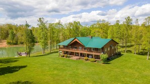 A lodge with a green roof, a porch, and a view of a lake.