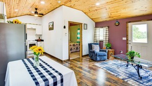 A spacious room with a wooden ceiling, a dining table with a checkered tablecloth, a blue armchair, and a glass coffee table. - Northeast Texas Vacation Rental ~ 6 Mi to Commerce (Commerce)