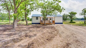 A small, single-story building with a porch, surrounded by trees and a dirt path. - Northeast Texas Vacation Rental ~ 6 Mi to Commerce (Commerce)