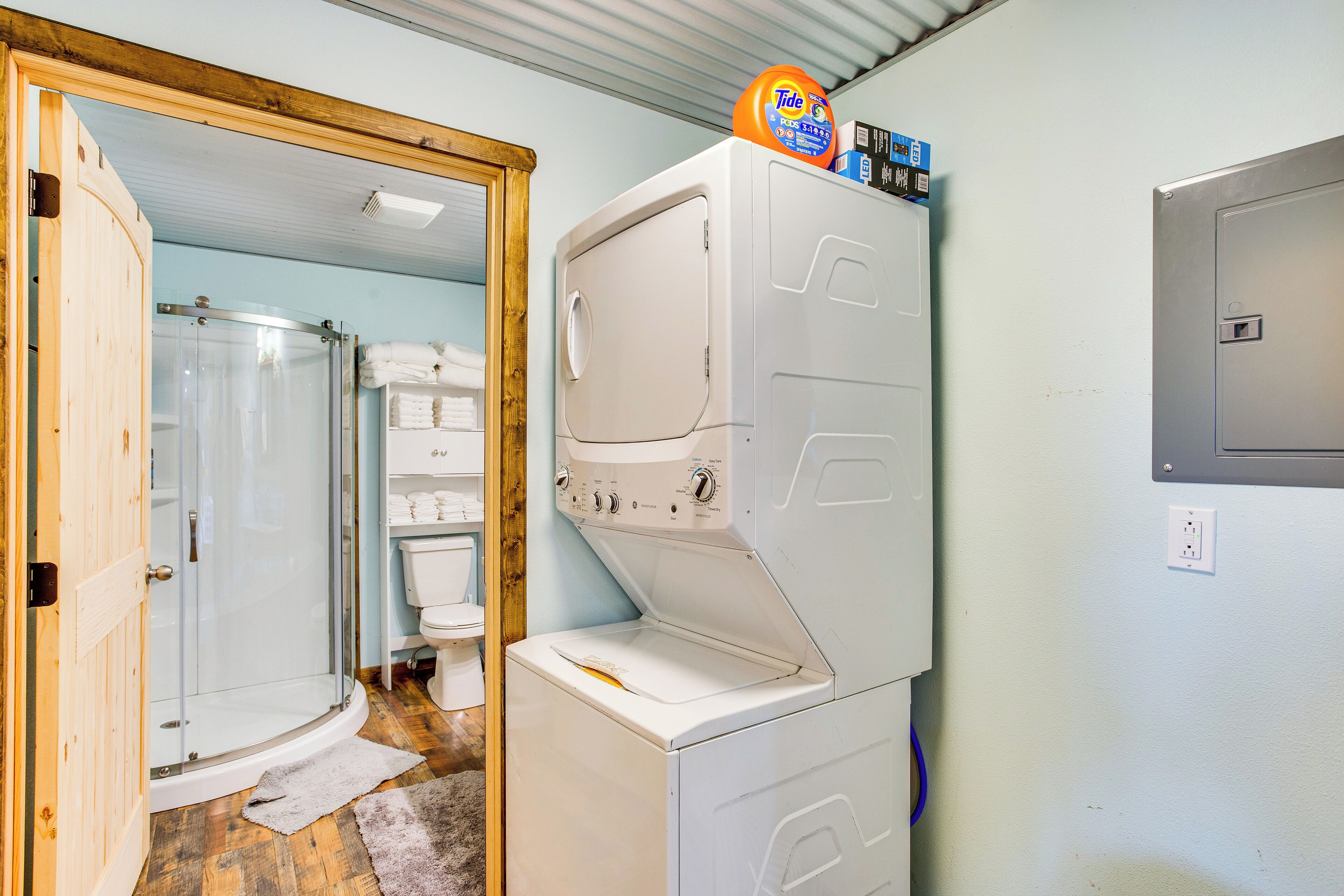 A laundry area with stacked washers and dryers, a shower, and a toilet.