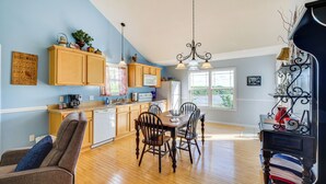 A modern kitchen with wooden cabinets, a dining table, and chairs. There is a microwave, a coffee maker, and a refrigerator. - Cozy Cottage in Taylorsville: Hot Tub & Lake Views (Taylorsville)