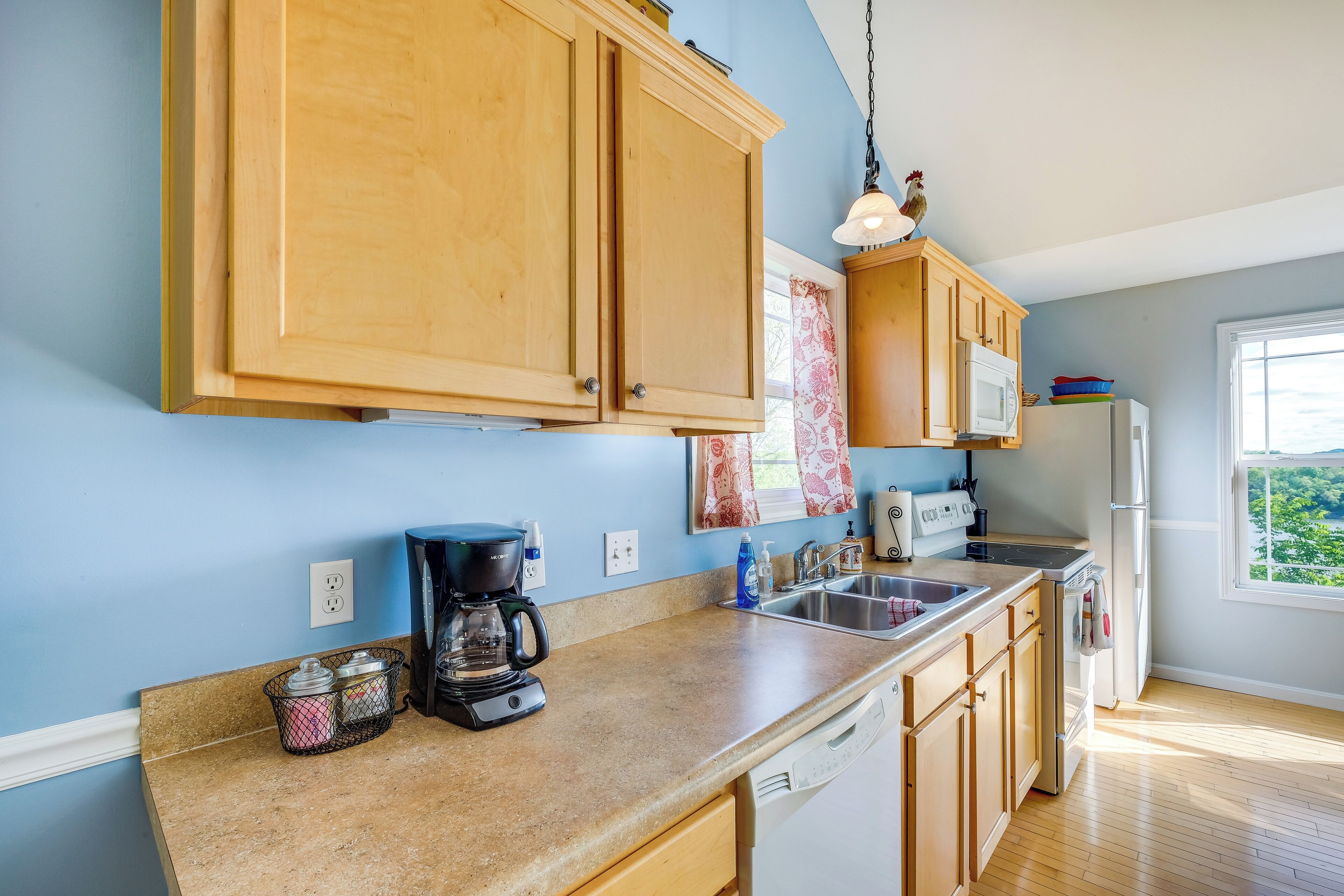 Una cocina con armarios de madera, cafetera, microondas y refrigerador.