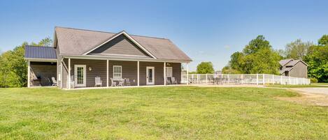 A two-story house with a covered porch, a fenced backyard, and a small detached garage.