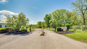 A gated driveway leading to a building with a metal roof, surrounded by greenery and a clear sky. - Cozy Cottage in Taylorsville: Hot Tub & Lake Views (Taylorsville)