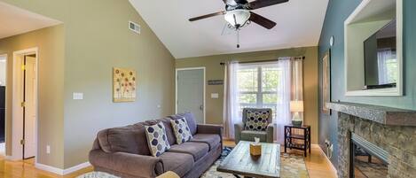 A living room with a brown sofa, a coffee table, a fireplace, and a ceiling fan.