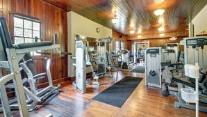 Une salle de sport équipée de divers appareils d’exercice, avec des murs en bois et un grand miroir.