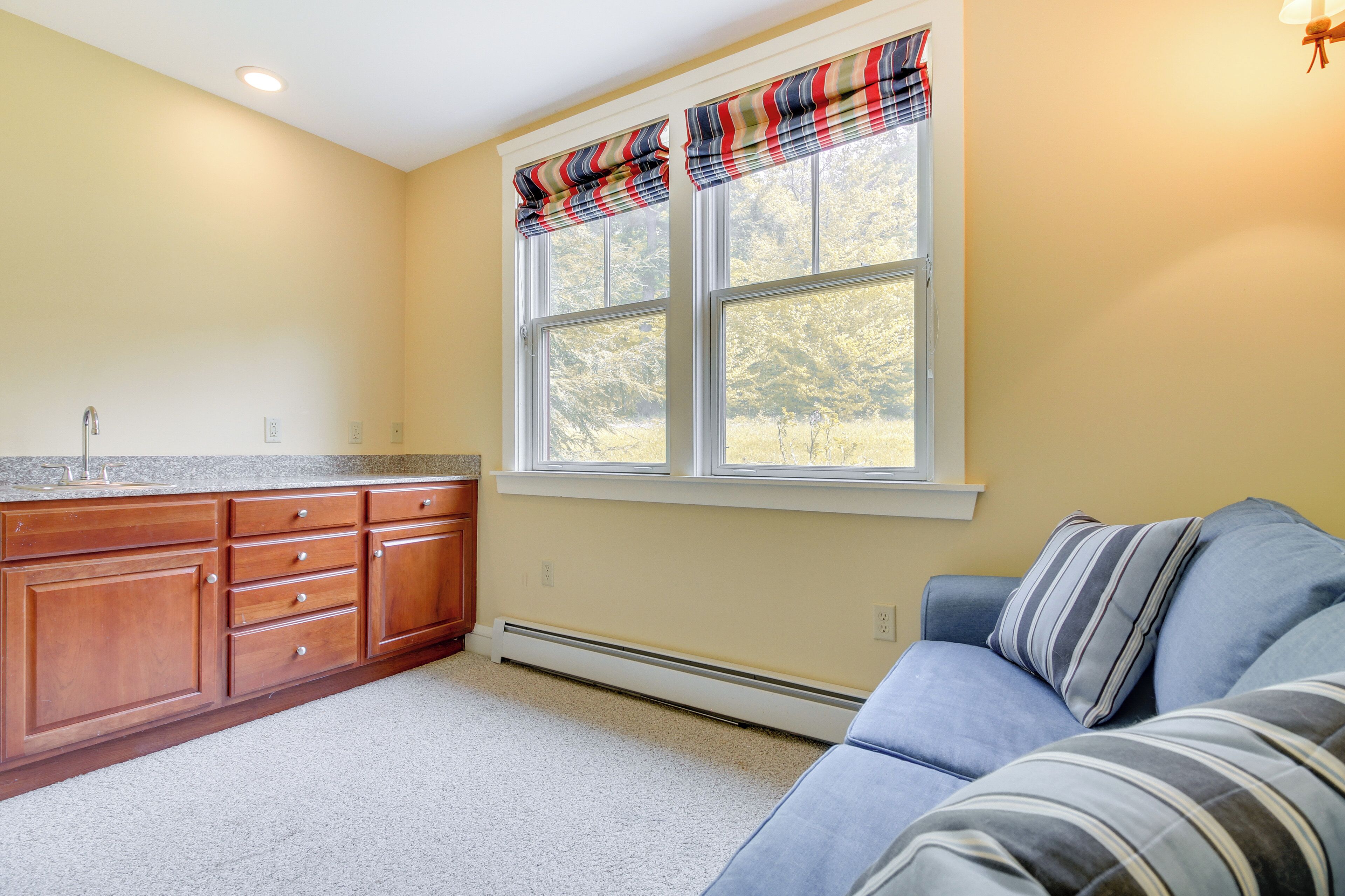 A kitchen with wooden cabinets, a built-in stove, and a window with striped valance.