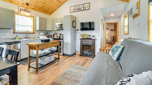 A cozy kitchen with a dining area, a fireplace, and a living room with a sofa. - Cozy New York Abode - Porch, Near Fishing & Hiking (Jordan)