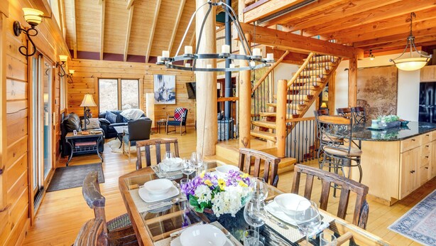 A wooden cabin interior with a dining area, kitchen, and living room. - Berkshire Hills Nature Lovers' Log Home Retreat (Windsor)