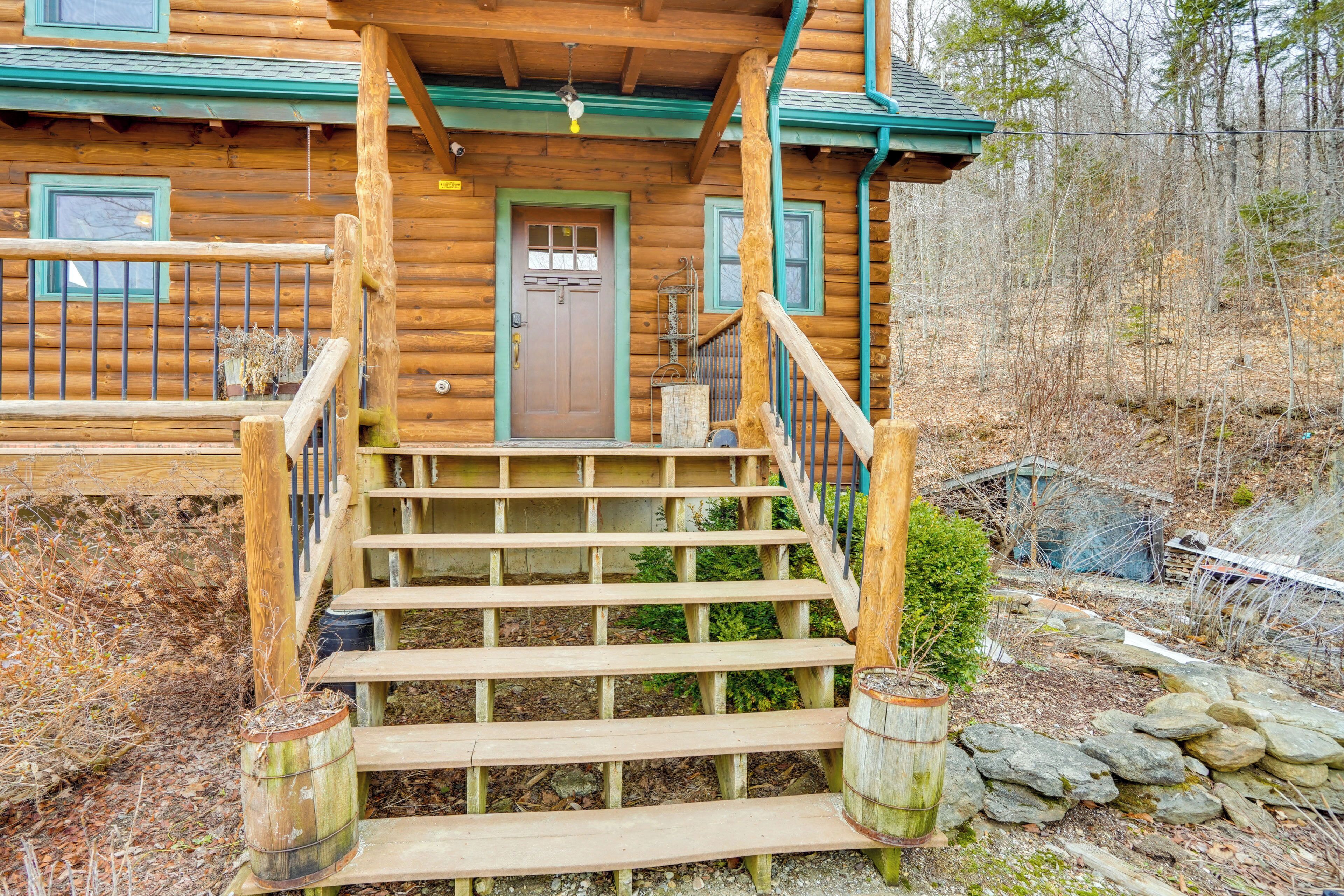 Une cabane en bois avec un porche à l’avant, des marches en bois et un mur en pierre.
