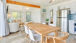 A spacious kitchen with a wooden dining table, white chairs, and modern appliances. - Beachy Palms Cottage on Lake Huron w/ Hot Tub! (Palms)