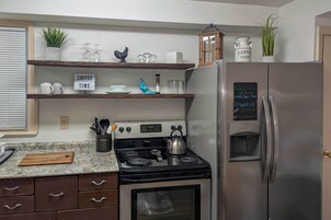 Una cocina con estufa, refrigerador, estantes de madera y un letrero de café.