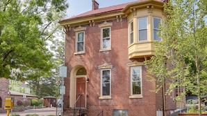 A two-story brick building with a red roof, a bay window on the second floor, and a front door with a small porch. - Walk to Restaurants & Shops: Apt in Pennsylvania! (Pottstown)