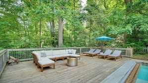 A wooden deck with a sofa, lounge chairs, a fire pit, and a pool. - Maryland Vacation Rental w/ Private Pool & Dock (Lusby)