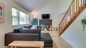 A living room with a dark sofa, wooden coffee table, and a fireplace. - Maryland Vacation Rental w/ Private Pool & Dock (Lusby)