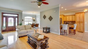 A spacious living room with a wooden coffee table, a sofa, and a dining area with wooden chairs and a kitchen in the background. - Muscle Shoals Home < 3 Mi to Recording Studios! (Muscle Shoals)