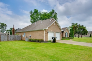 A two-story brick house with a garage, a well-maintained lawn, and a wooden fence. - Muscle Shoals Home < 3 Mi to Recording Studios! (Muscle Shoals)