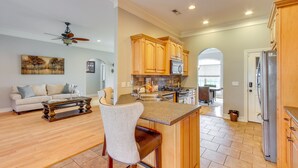 A spacious kitchen with wooden cabinets, a central island, and a dining area with a sofa and coffee table. - Muscle Shoals Home < 3 Mi to Recording Studios! (Muscle Shoals)