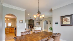 A spacious dining area with a large wooden table and leather chairs, a chandelier, and a fireplace in the background. - Muscle Shoals Home < 3 Mi to Recording Studios! (Muscle Shoals)