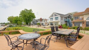 A deck with outdoor furniture, a view of houses, and a grassy area.