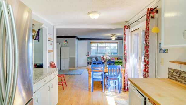 A kitchen with wooden cabinets, a stainless steel refrigerator, and a dining area with blue chairs and a wooden table. - Vancouver Vacation Rental ~ 16 Mi to Portland! (Vancouver)