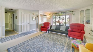A living room with a patterned rug, a red armchair, a green sofa, and a colorful ottoman. - Vancouver Vacation Rental ~ 16 Mi to Portland! (Vancouver)