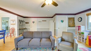 A living room with a gray sofa, a tan armchair, a patterned rug, a ceiling fan, and a bookshelf. - Vancouver Vacation Rental ~ 16 Mi to Portland! (Vancouver)