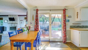 A dining area with a wooden table and blue chairs, a stone fireplace, and a view of the backyard through a glass door. - Vancouver Vacation Rental ~ 16 Mi to Portland! (Vancouver)