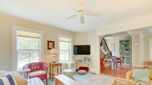 A living room with a television, a red wicker chair, a white sofa, and a wooden bench. - Georgetown Vacation Rental: Gas Grill & Near Beach (Georgetown)