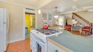 A kitchen with a gas stove, a refrigerator, and a dining area with chairs and a table. - Georgetown Vacation Rental: Gas Grill & Near Beach (Georgetown)