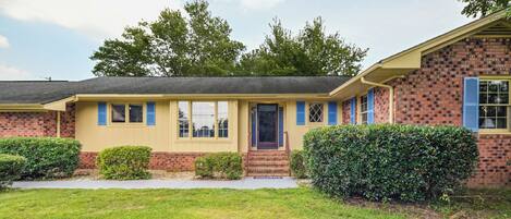 A two-story house with a brick facade, a front porch, and a well-maintained lawn.
