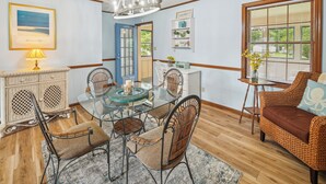 A dining area with a glass table, wicker chairs, a chandelier, and a view of the outdoors through a window. - 6 Mi to Beach: Myrtle Beach Escape w/ Sunroom! (Myrtle Beach)
