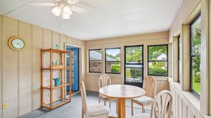 A dining area with a round wooden table and four chairs, a bamboo shelf unit, and a clock on the wall. - 6 Mi to Beach: Myrtle Beach Escape w/ Sunroom! (Myrtle Beach)