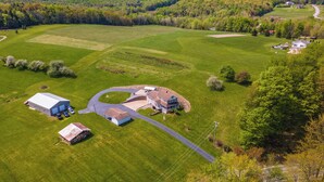 An aerial view of a rural property with a large house, barns, and expansive green fields. - Spacious Pennsylvania Vacation Rental w/ Backyard (Kersey)