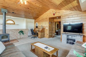 A cozy living room with a fireplace, wooden walls, a TV, and a comfortable seating area.