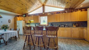 A spacious kitchen with wooden cabinets, a large window, and a dining area with a table and chairs. - Spacious Pennsylvania Vacation Rental w/ Backyard (Kersey)