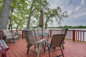 A wooden deck with outdoor furniture, including chairs and a table, overlooking a body of water. - Decatur House: Fishing, Skiing, & Golfing! (Decatur)