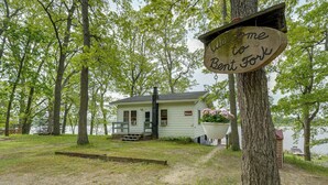 Eine Hütte mit einem Schild "Welcome to Benton Fork", umgeben von Bäumen und einem See.