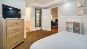 A bedroom with a bed, a TV on a dresser, a door leading to another room, and a wall with artwork. - Walk to Atlantic Beach: Family Gem w/ Fenced Yard (North Myrtle Beach)