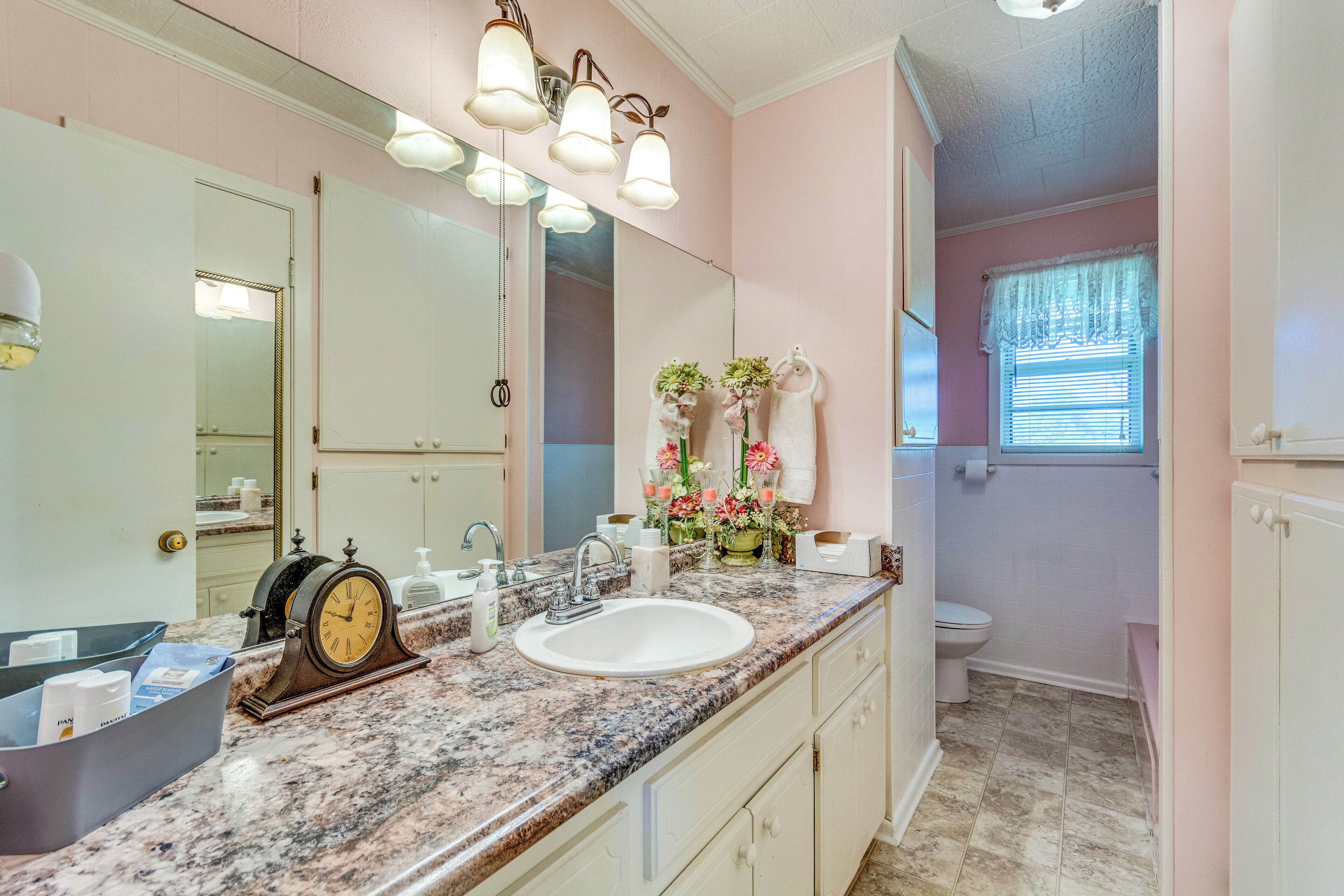 A bathroom with a sink, mirror, and vanity.