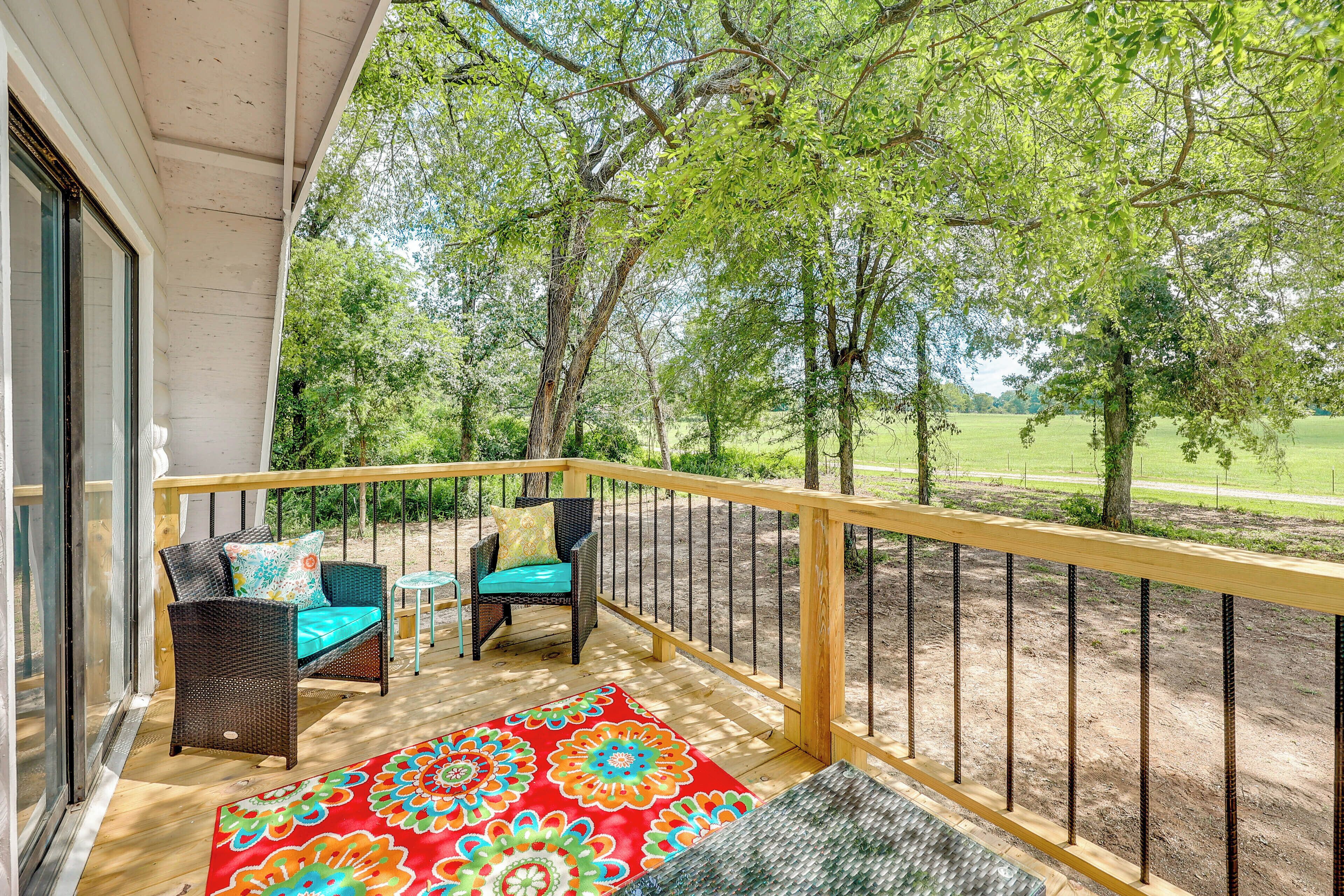 A wooden deck with wicker furniture and a colorful rug.