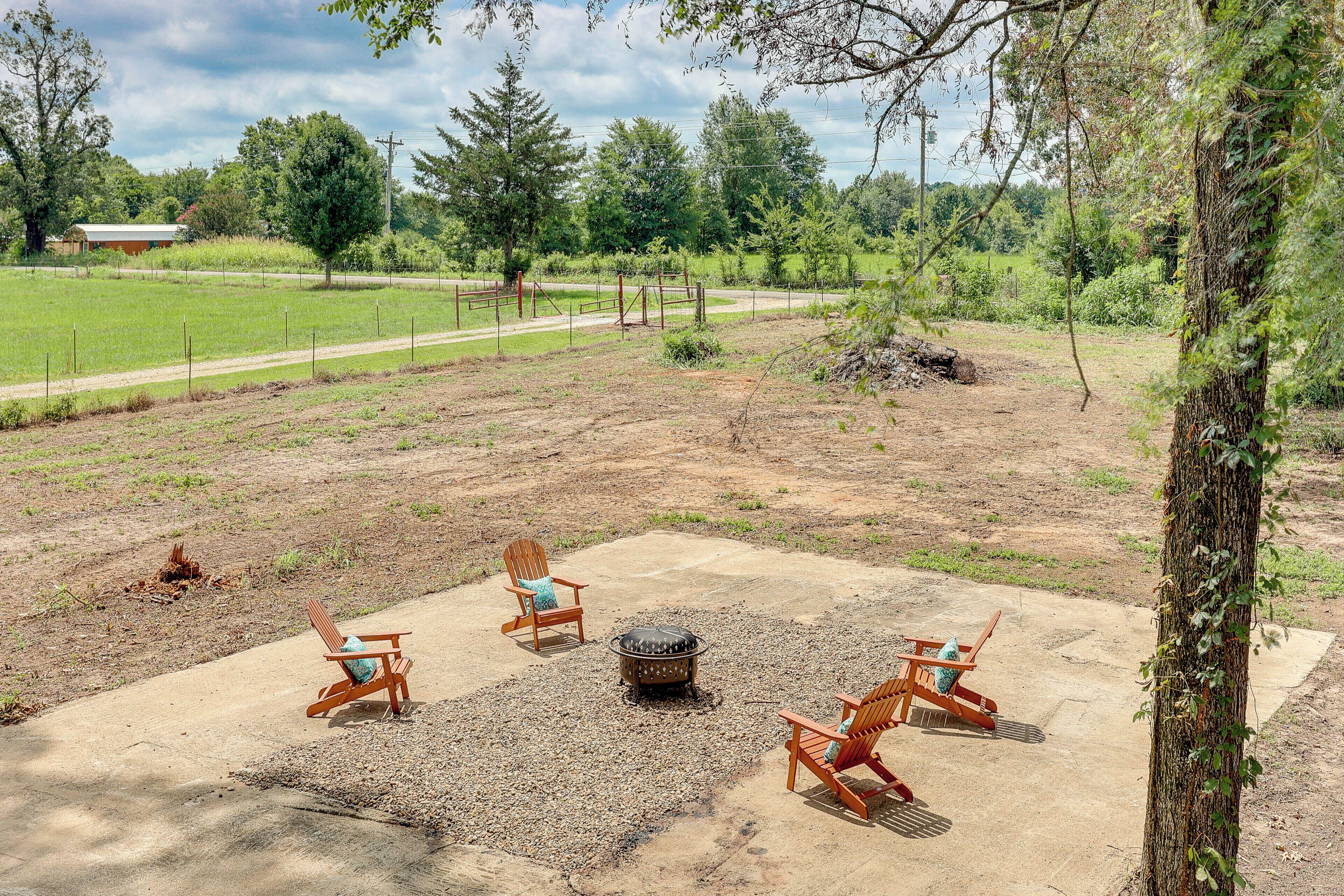 A fenced outdoor area with a fire pit and four Adirondack chairs.