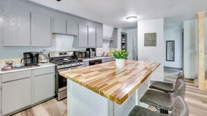 Una cocina moderna con gabinetes grises, una isla de madera y un horno empotrado.