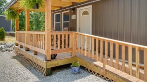 Une terrasse en bois avec une rambarde, une pancarte de bienvenue et une porte.