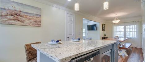 A modern kitchen with a granite countertop, stainless steel appliances, and pendant lighting.