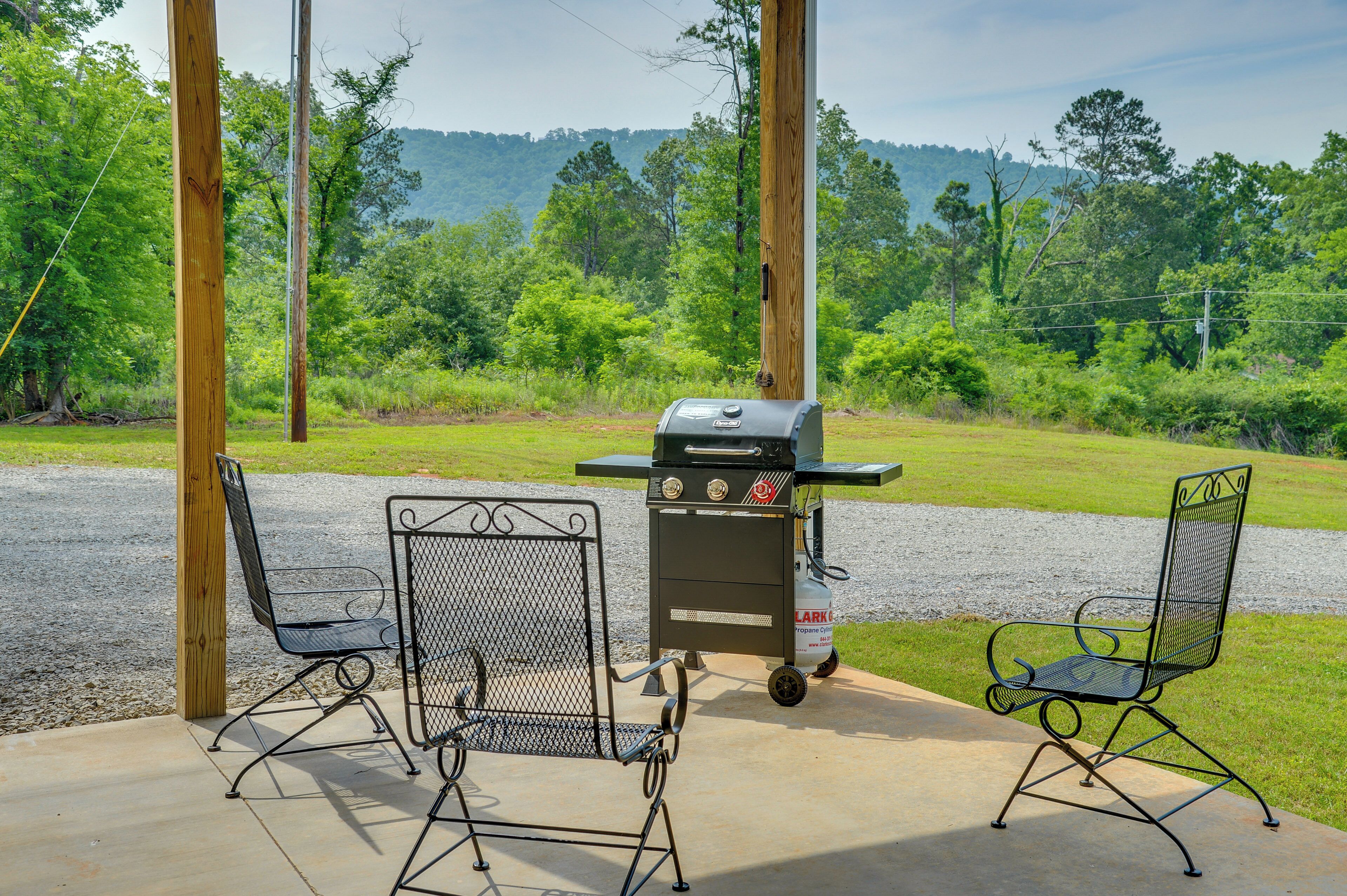A patio area with two metal chairs, a grill, and a concrete floor.