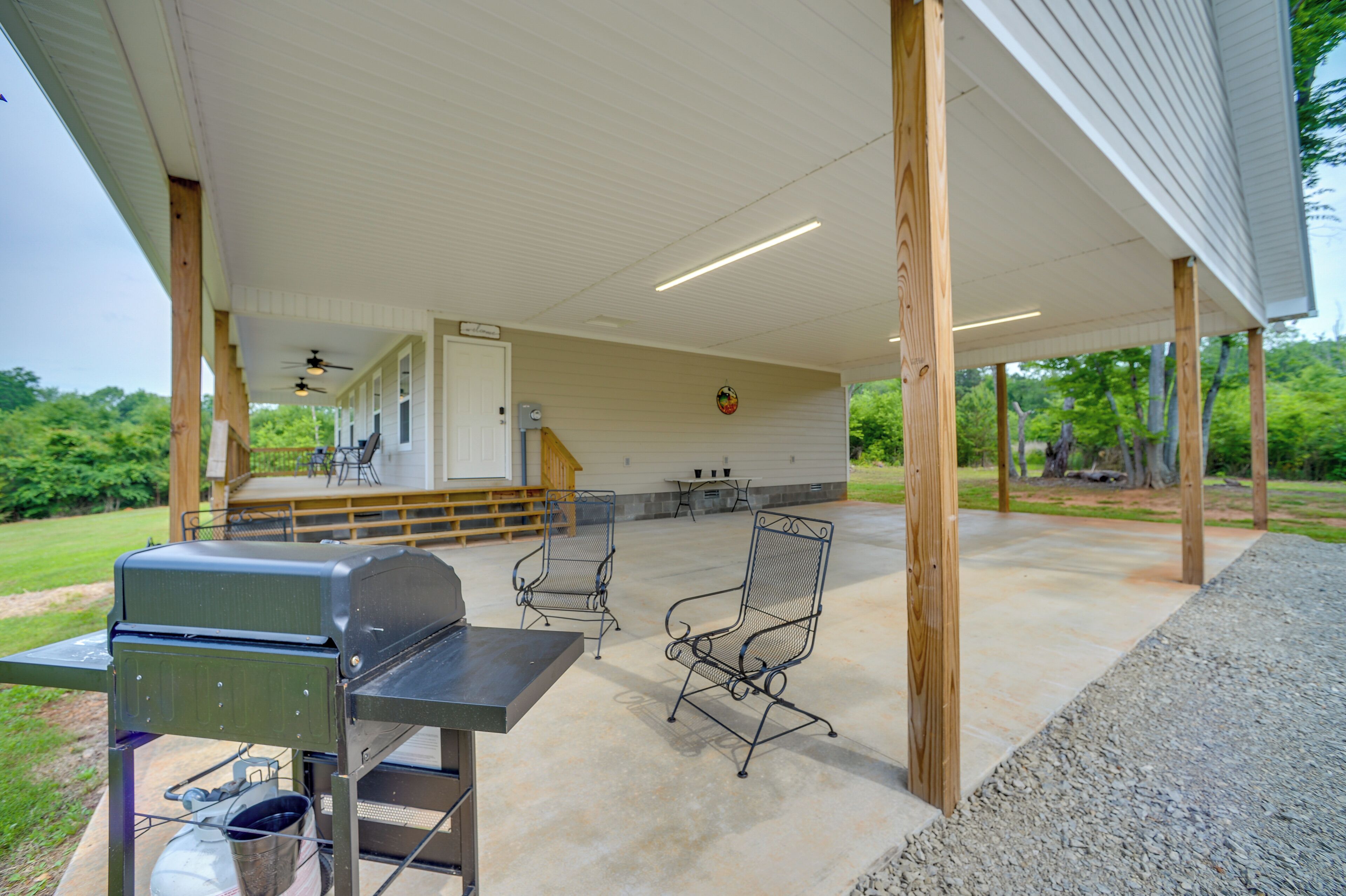 An outdoor patio with a grill, two metal chairs, and a table.