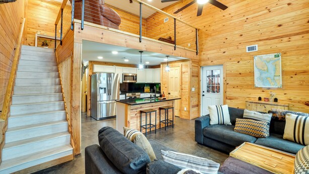 Eine geräumige Hütte mit Holzvertäfelung, einer Küche, einem Essbereich und einem Wohnzimmer mit Sofa und Couchtisch.