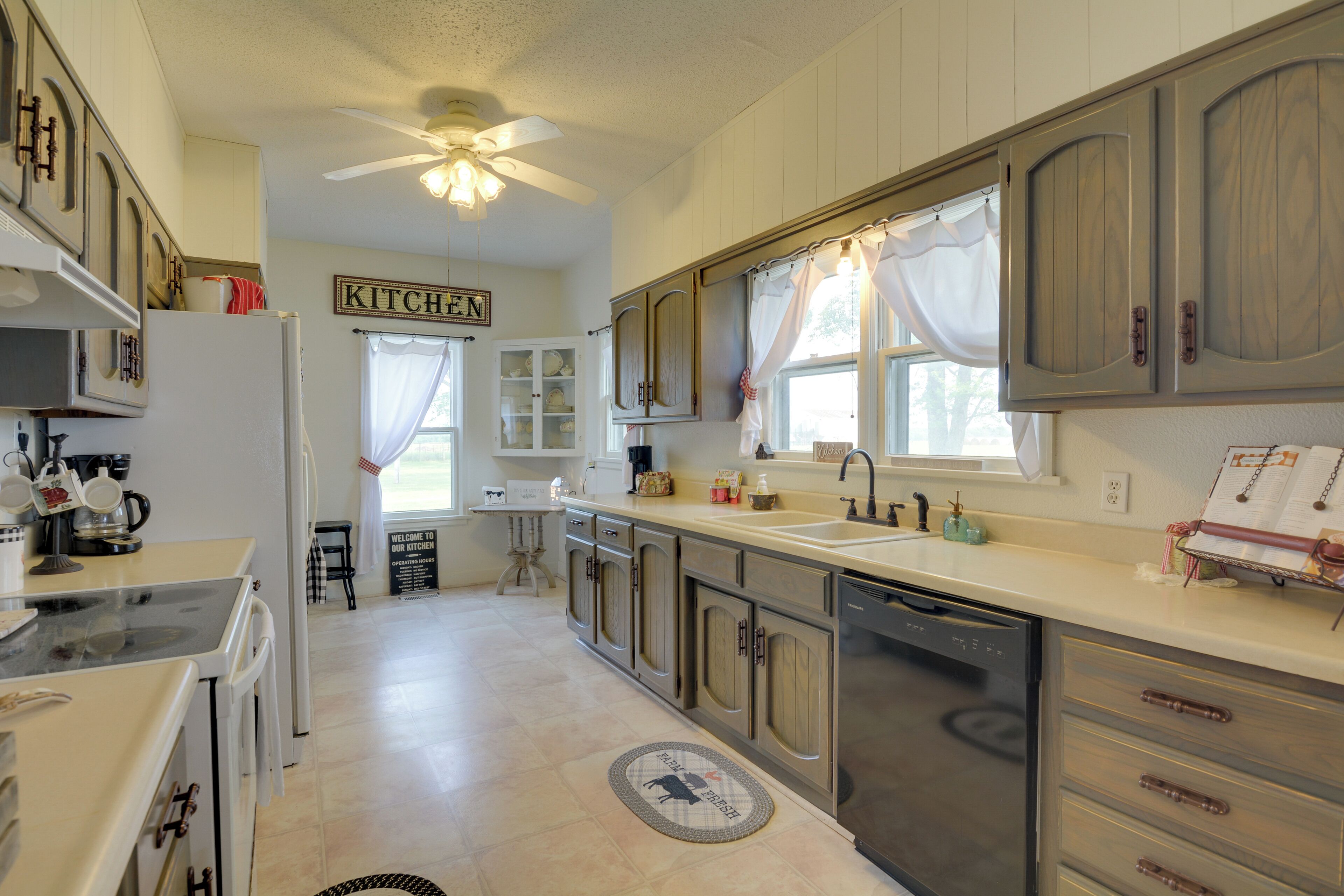 A kitchen with wooden cabinets, a dishwasher, and a ceiling fan.