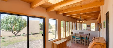 Una habitación amplia con ventanas grandes, techo de madera y suelo de piedra.